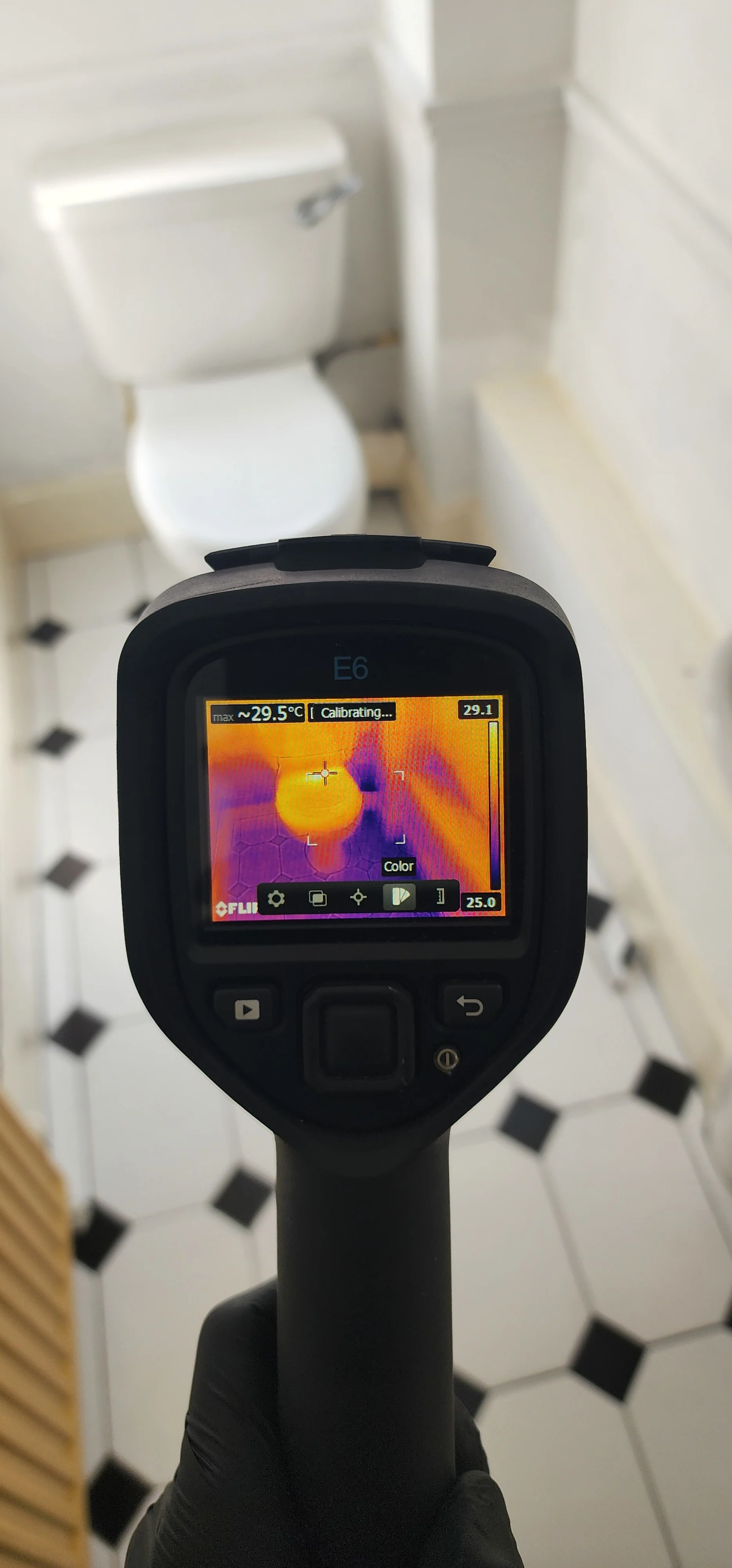 Thermal camera displaying a temperature pattern on tiled flooring beside a toilet