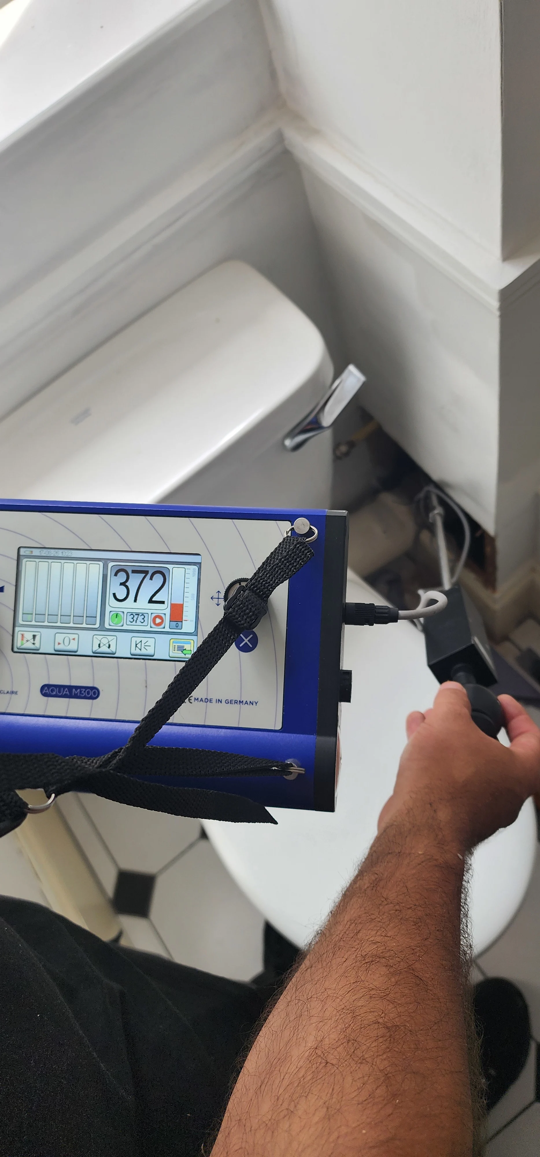 Handheld leak investigation equipment used beside a toilet in the inspected area