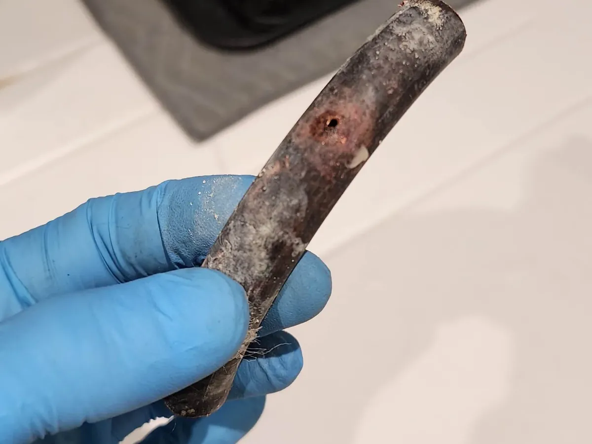 Damaged hot water pipe section held during Camberley investigation