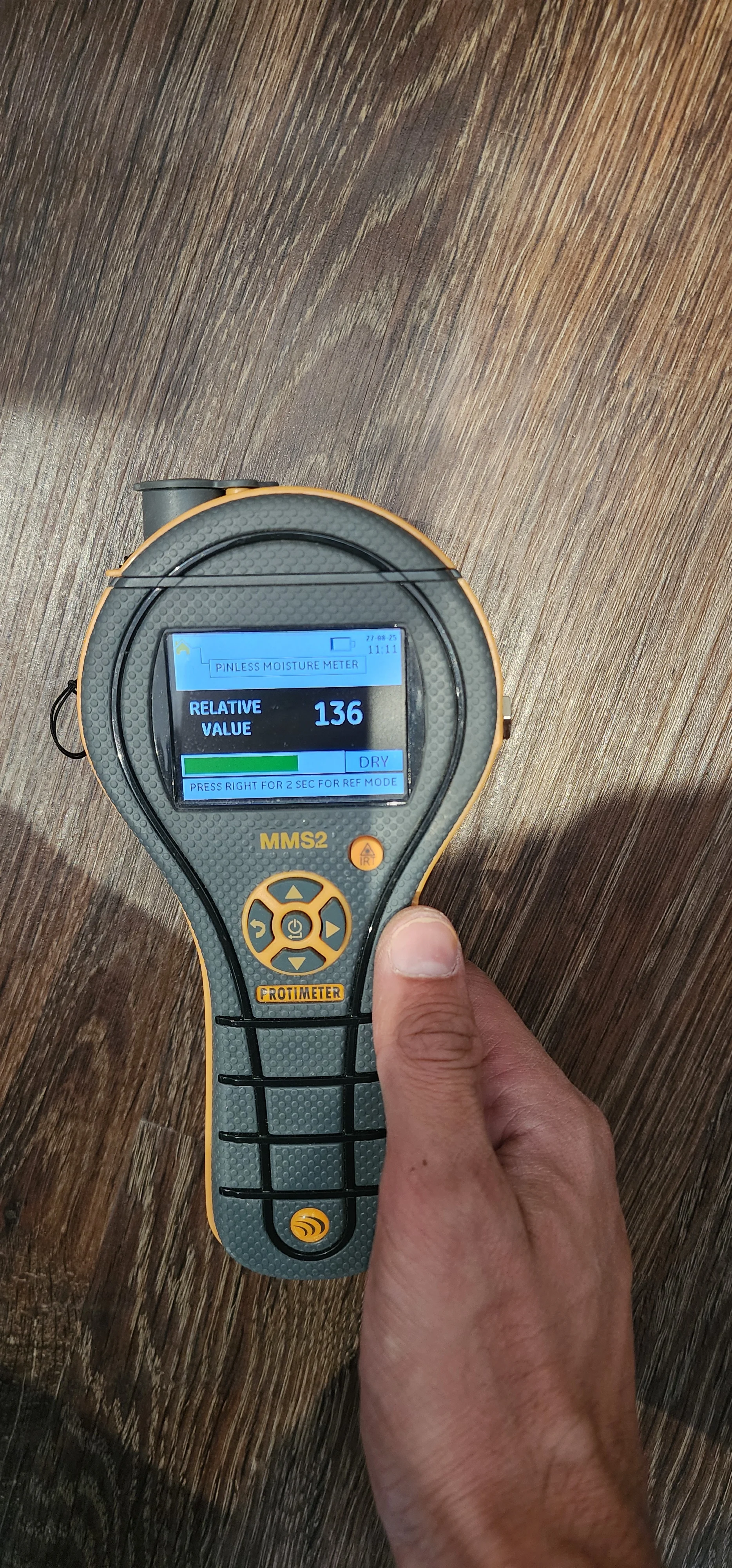 Pinless moisture meter held over wood-effect flooring