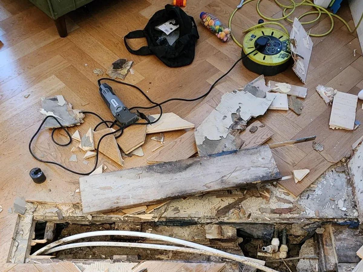 Underfloor leak investigation area with exposed materials and diagnostic equipment